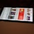 A smartphone displaying a streaming app interface, showing various movie and TV show thumbnails. The screen includes categories like 'For you' and 'New release hit films', with images from popular films. The background is a dimly lit setting with a fabric surface.