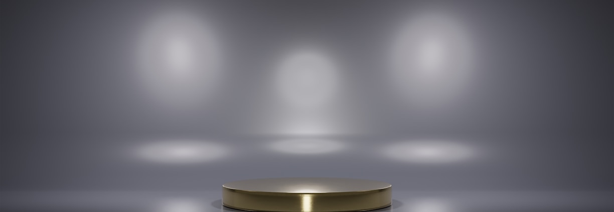 A metallic platform is centered in a minimalistic setting with a reflective surface. Soft, diffused lighting creates circular patterns on the background wall, enhancing the focus on the central stage. The ambiance is sleek and modern, with a hint of elegance.